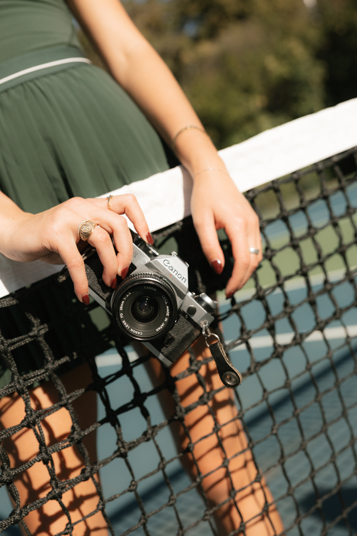 Hands holding a vintage camera over a tennis net